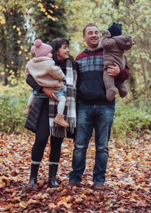 Young family all huddled together having a cuddle, in the autumnal leaves, orange and brown.