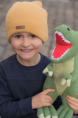 Little boy smiling, holding a toy dinosaur
