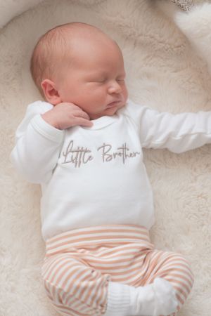 A newborn baby laying on a soft blanket within a baby basket. Neutral colours.