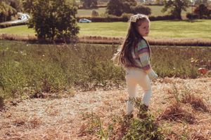 Young girl walking in field of long grass. looking over her shoulder.