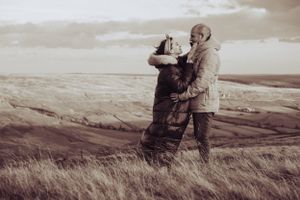 Black and white, young couple gazing at each other, fields in the background.