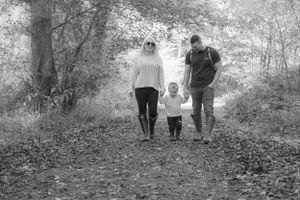 Black and white, couple holding little boys hands, walking towards the camera.