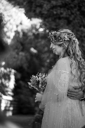 A bride and groom stood with arms around each other during their wedding ceremony. Black and white