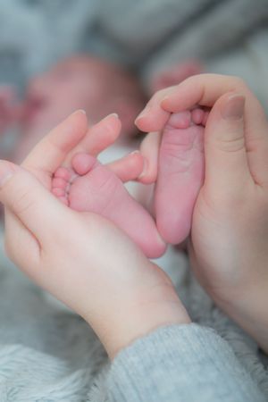 Newborn babys feet, being cradled by new mum.