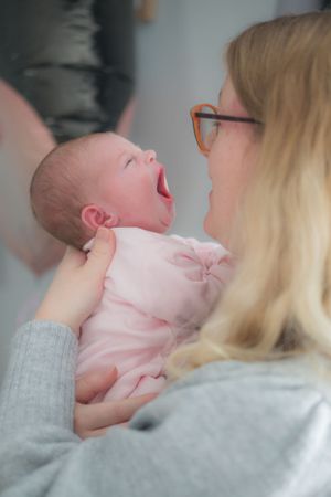 New mum holding newborn baby, newborn is yawning.