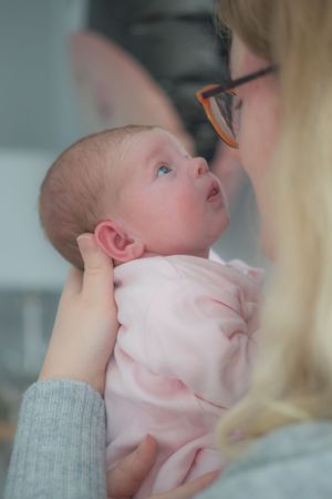 Newborn baby looking up to mum, wuth eyes open wide.