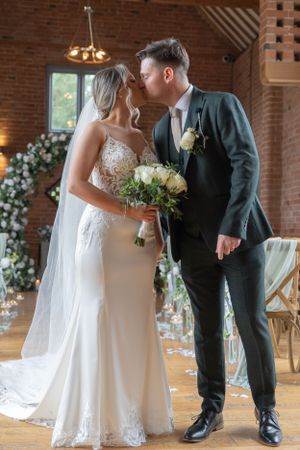 A bride and groom have just got married, they have walked down the aisle, they have stopped and going in for a kiss!