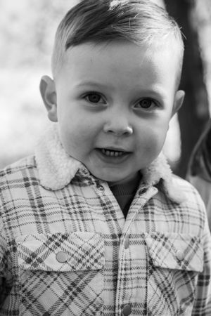 A black and white image of a little boy looking straight at the camera.