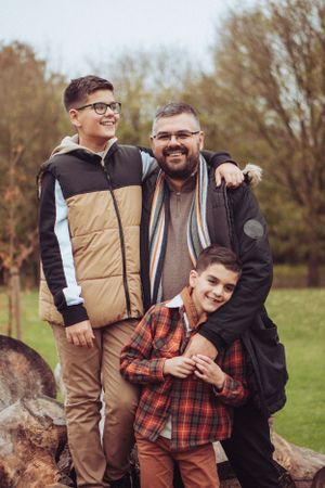 Dad with 2 sons, cuddled together and smiling.