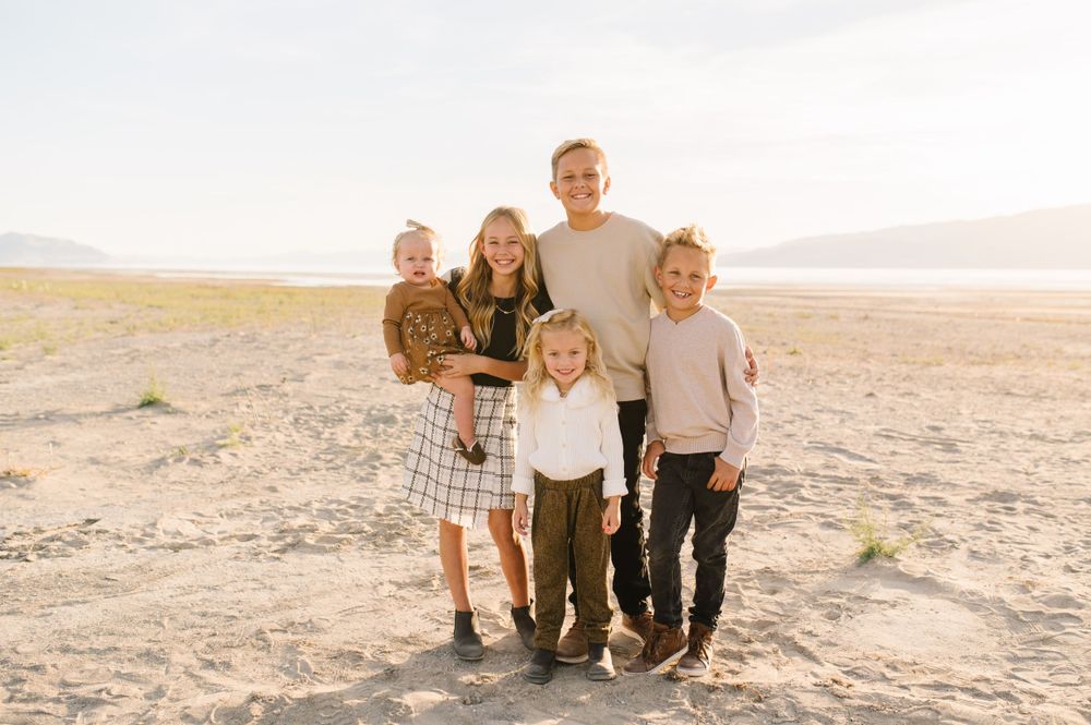 A group poses together in casual clothes against a desert landscape at sunset.