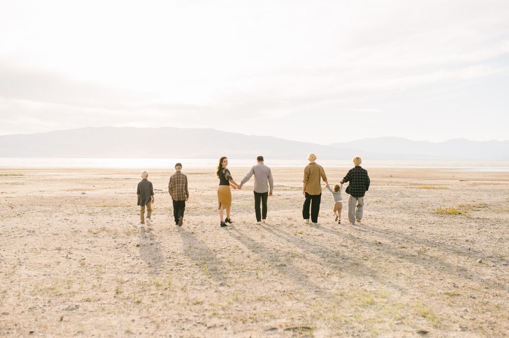 Group of people walking together on a desert plain at sunset casting long shadows.