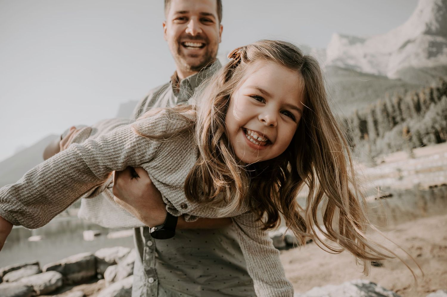A playful candid moment captured against a mountainous backdrop with flowing hair and joyful expressions.