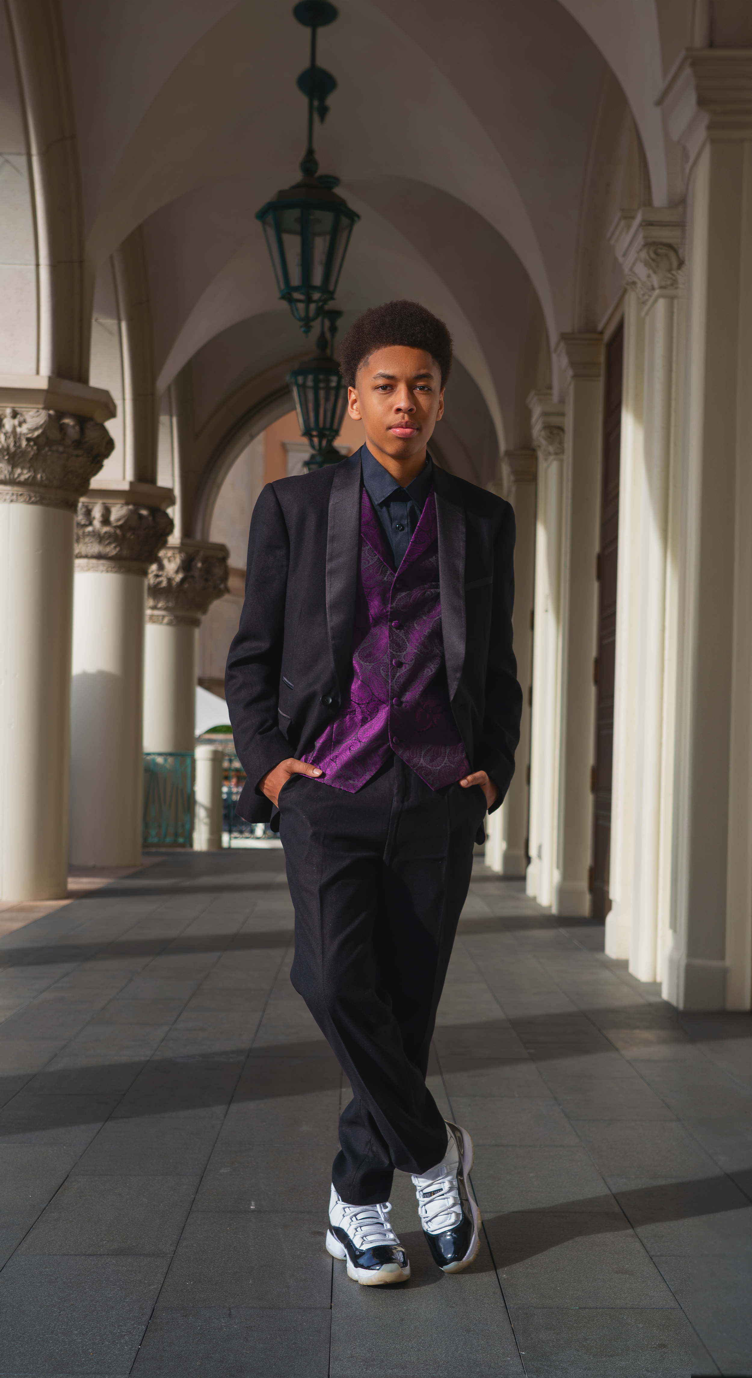 Portrait series in formal attire under arched colonnade with dramatic lighting.