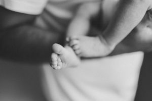 Close-up black and white photo of tiny baby feet against a light background.