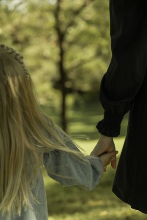 Silhouetted figures holding hands in soft natural lighting outdoors.