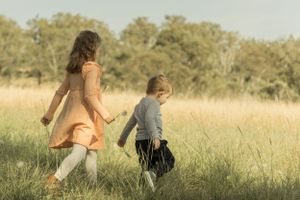 Two figures walking through a sun-lit golden field on a warm afternoon.