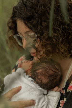 An intimate moment between parent and infant captured through natural foliage.