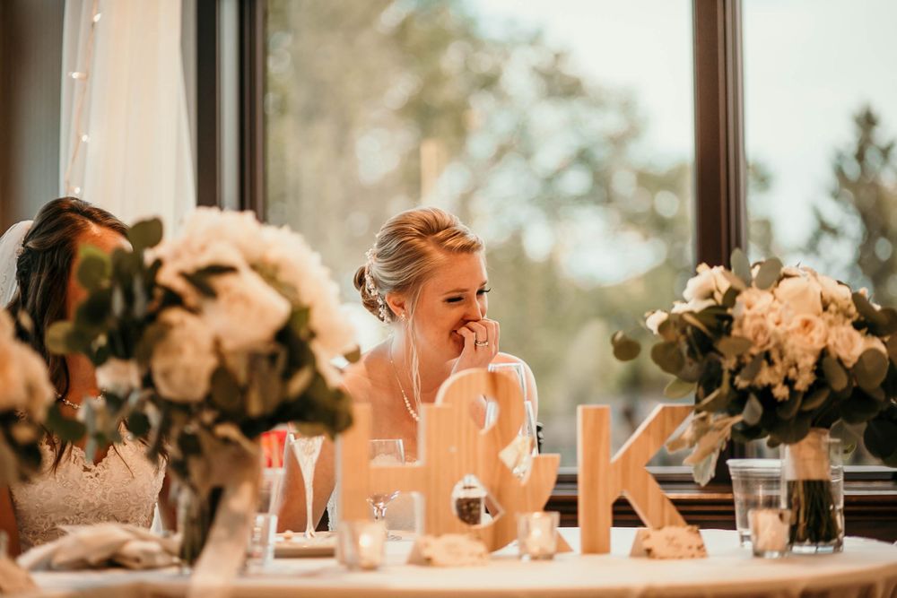 Bride laughing at the sweetheart table decorated with white flowers and monogram letters F and K.