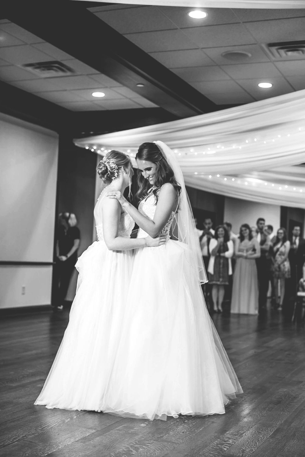 Black and white photo of two brides sharing emotional first dance together.