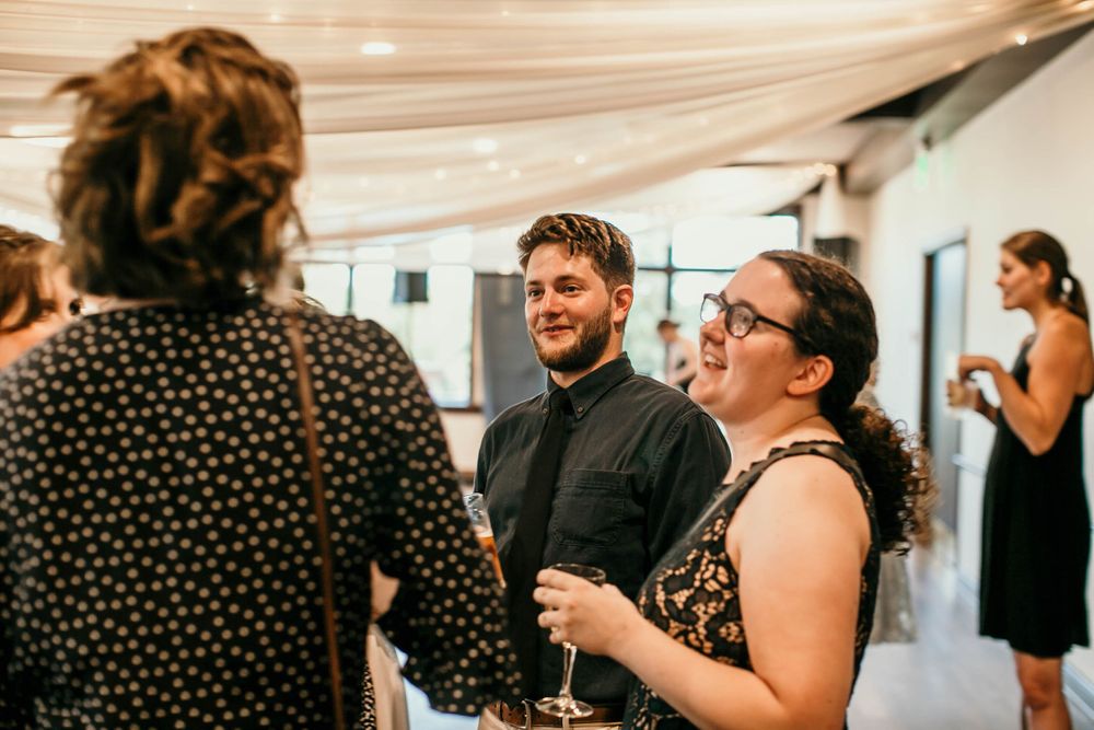 Guests laughing and socializing at an indoor wedding reception cocktail hour.