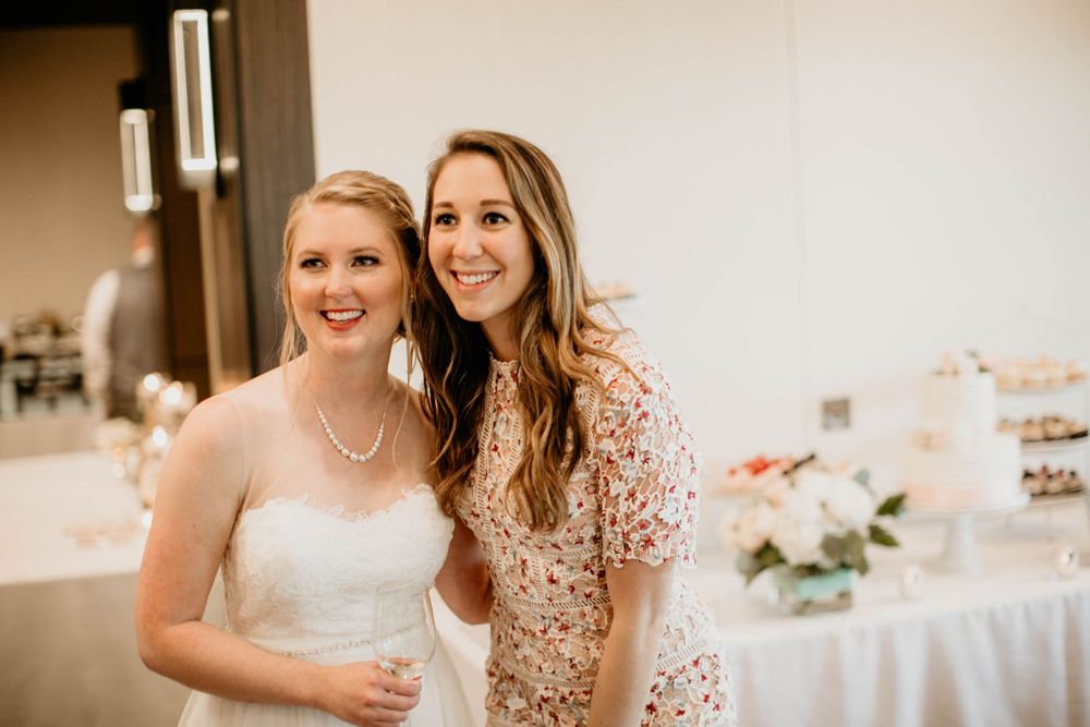 Two brides in white tulle gowns embrace and pose playfully together on wedding day.