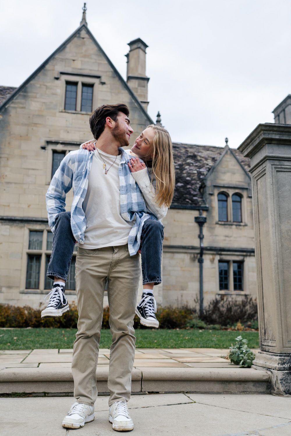 A couple in a field shares tender romantic moments wearing autumn coats against a natural outdoor backdrop.