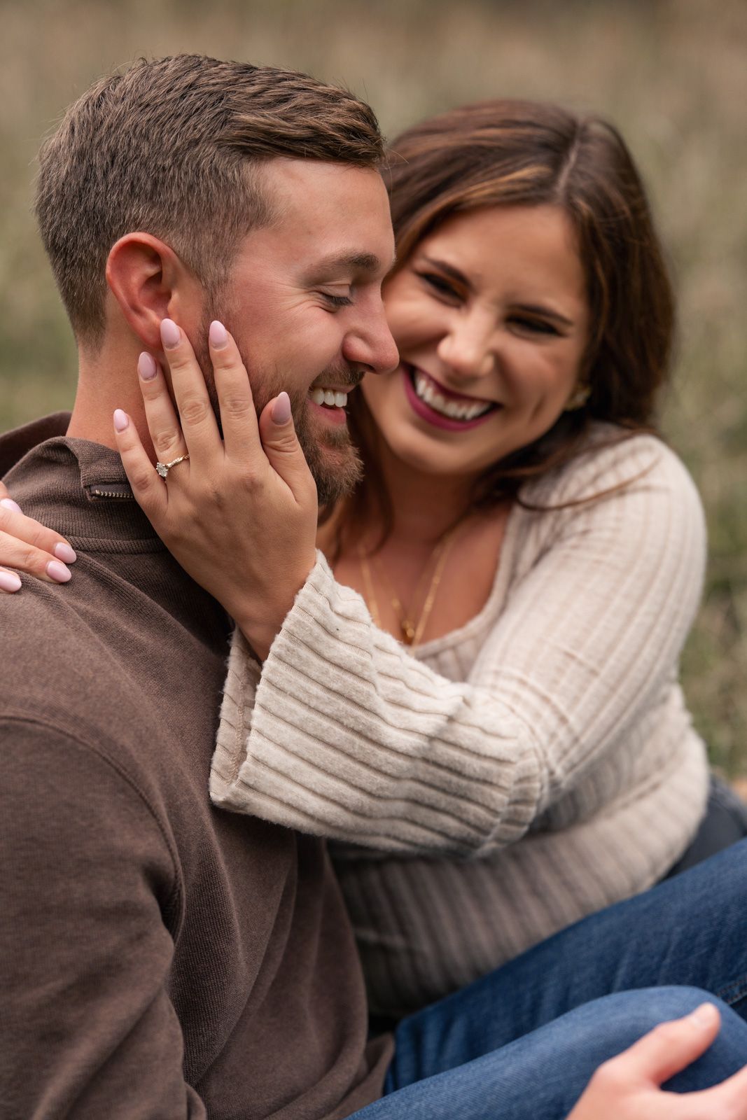 A couple shares a tender moment together while sitting outdoors in casual sweaters.