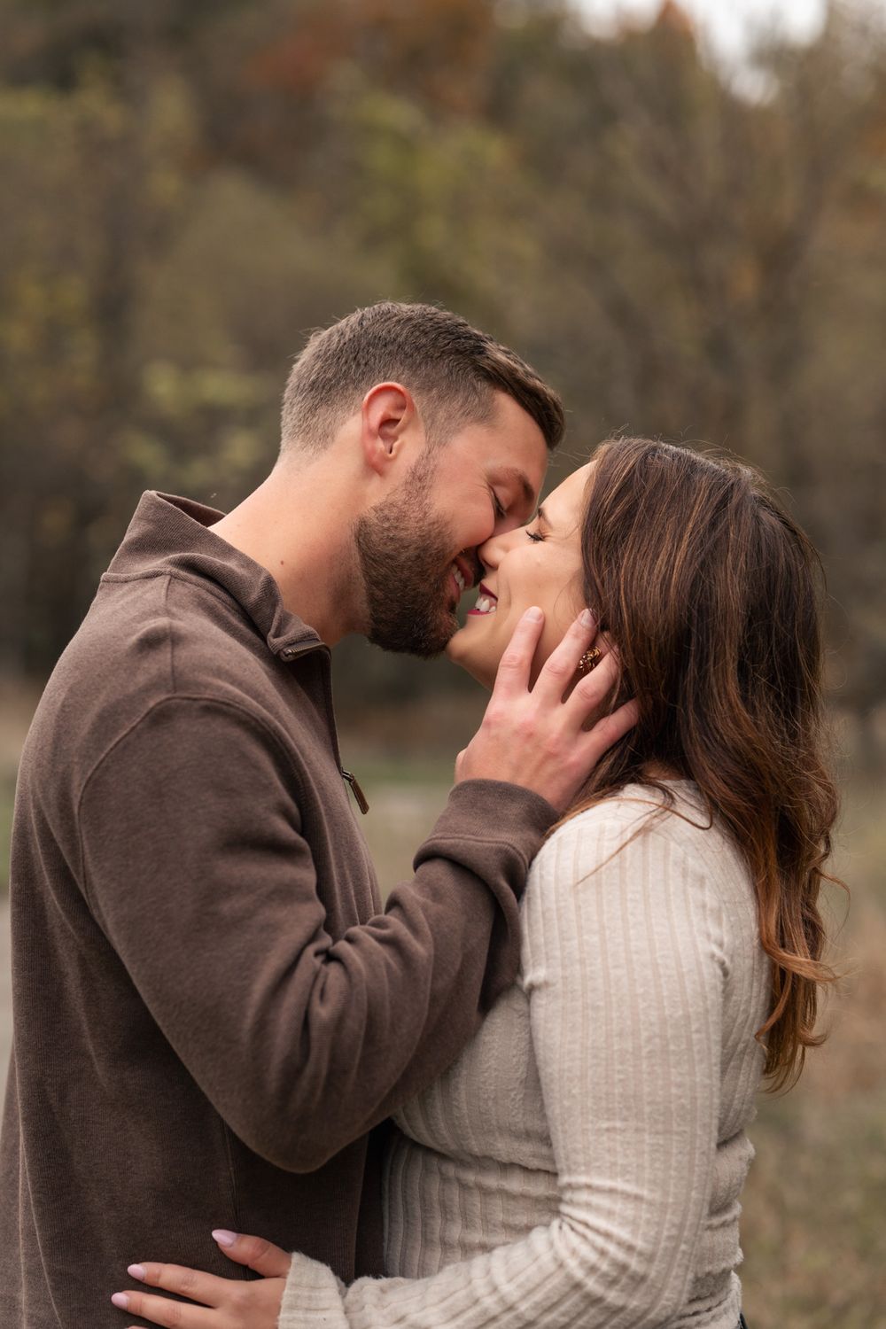 A romantic couple in warm sweaters share an intimate moment outdoors during autumn.