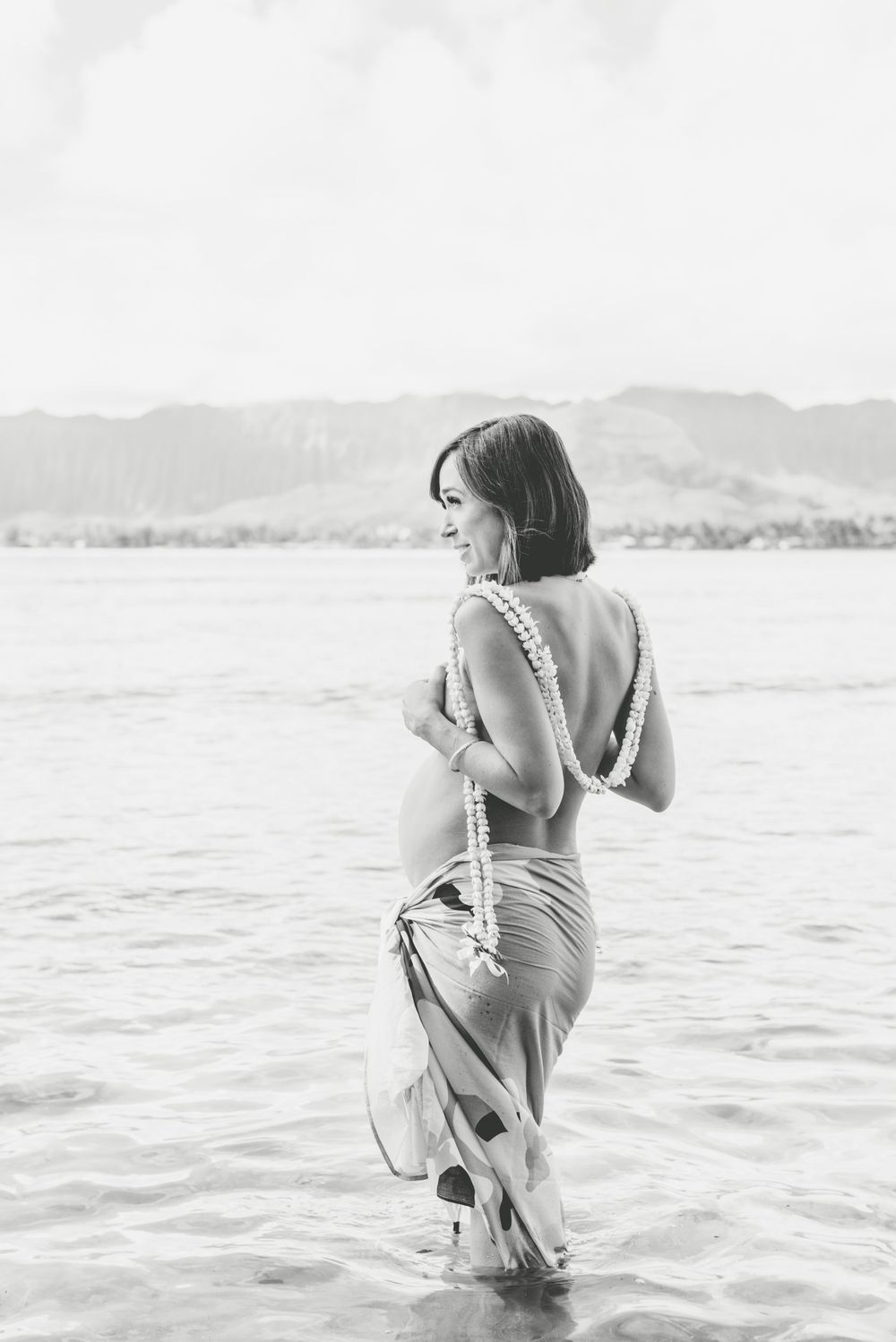 Maternity photos in Oahu with ocean and mountains backdrop.