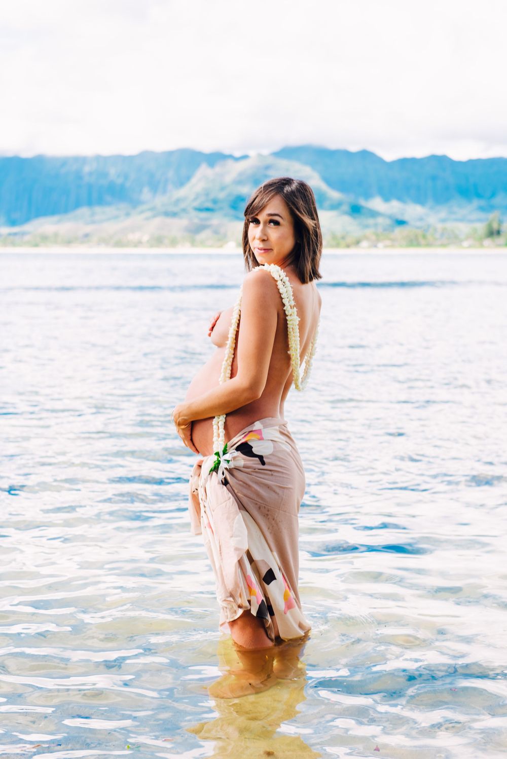 Maternity photos in Oahu with ocean and mountains backdrop.