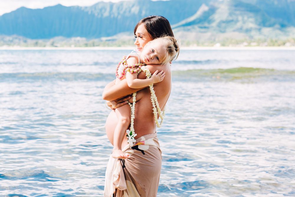 Maternity photos in Oahu with ocean and mountains backdrop.