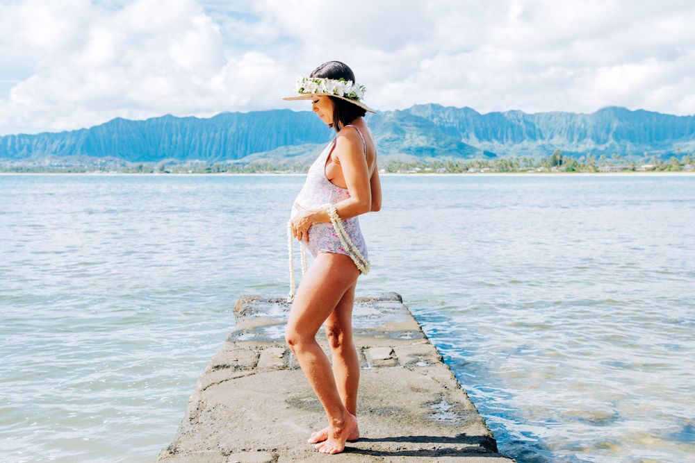 Maternity photos in Oahu with ocean and mountains backdrop.