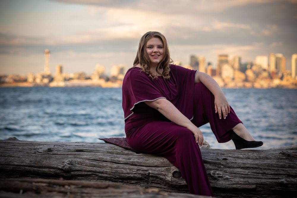 Seinor in Highschool sitting on long with Seattle in background.