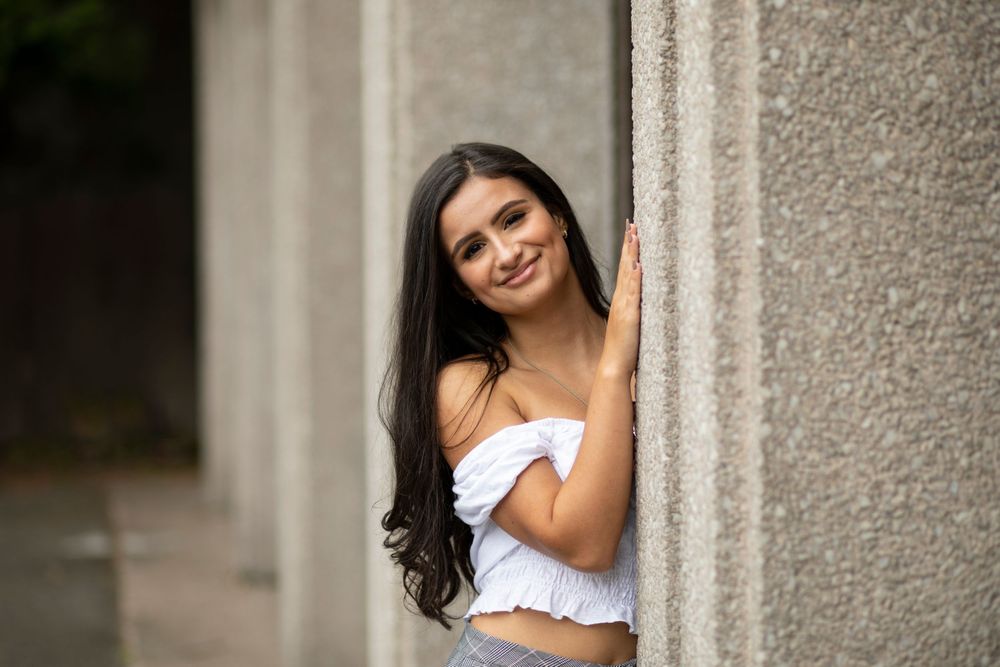 A teen girl standing next to a pillar.
