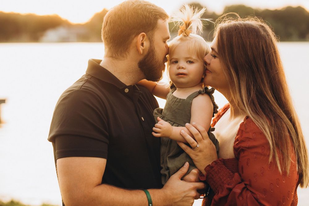 A family shares an intimate moment together by the water at sunset.