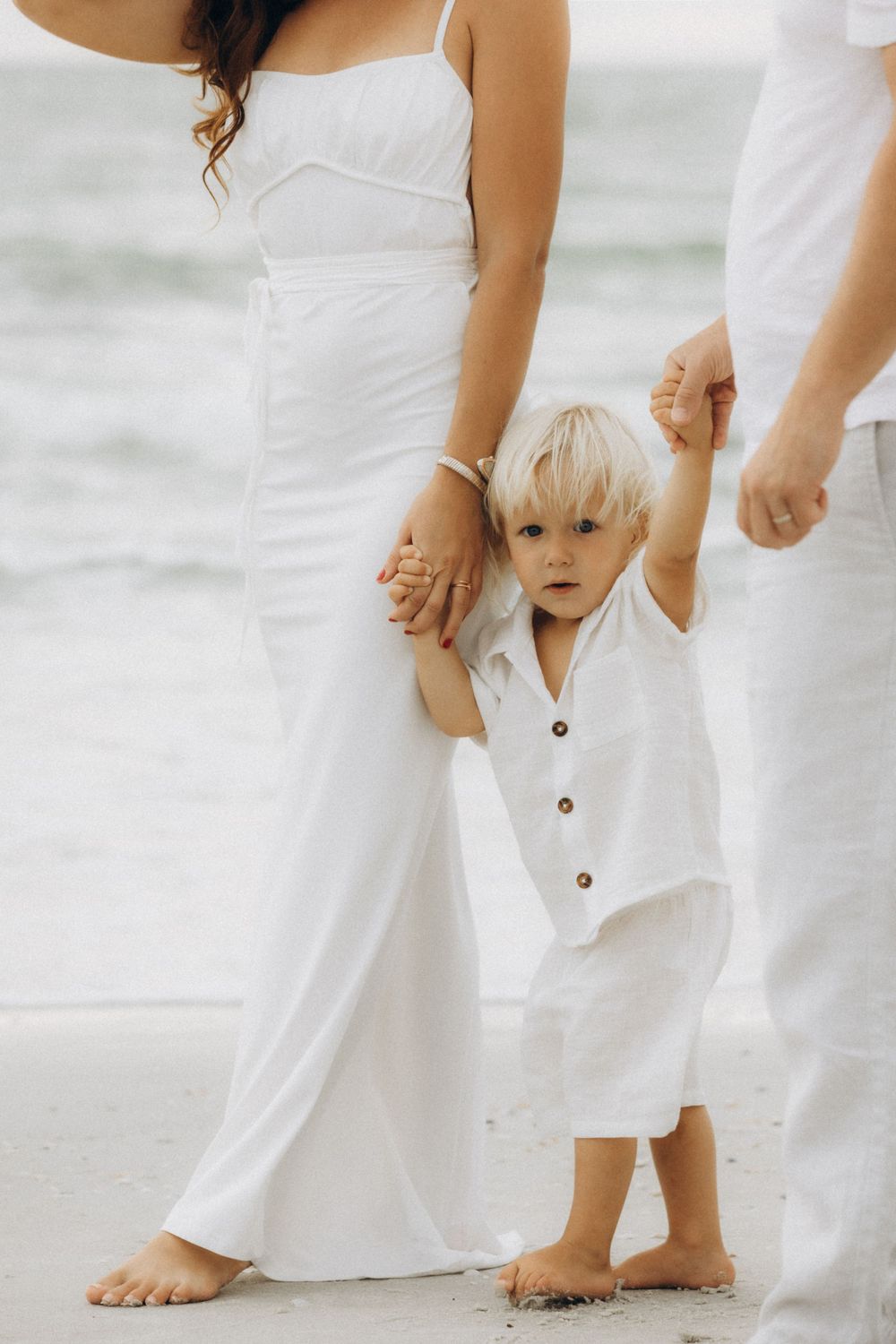 Close-up of family walking on beach in matching white outfits.