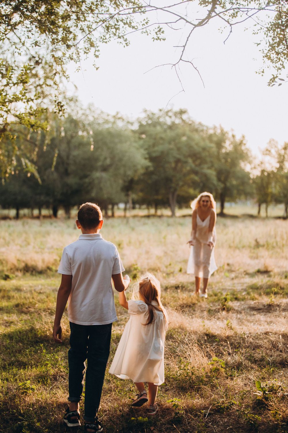 Family of three playing in sunlit field during golden hour.