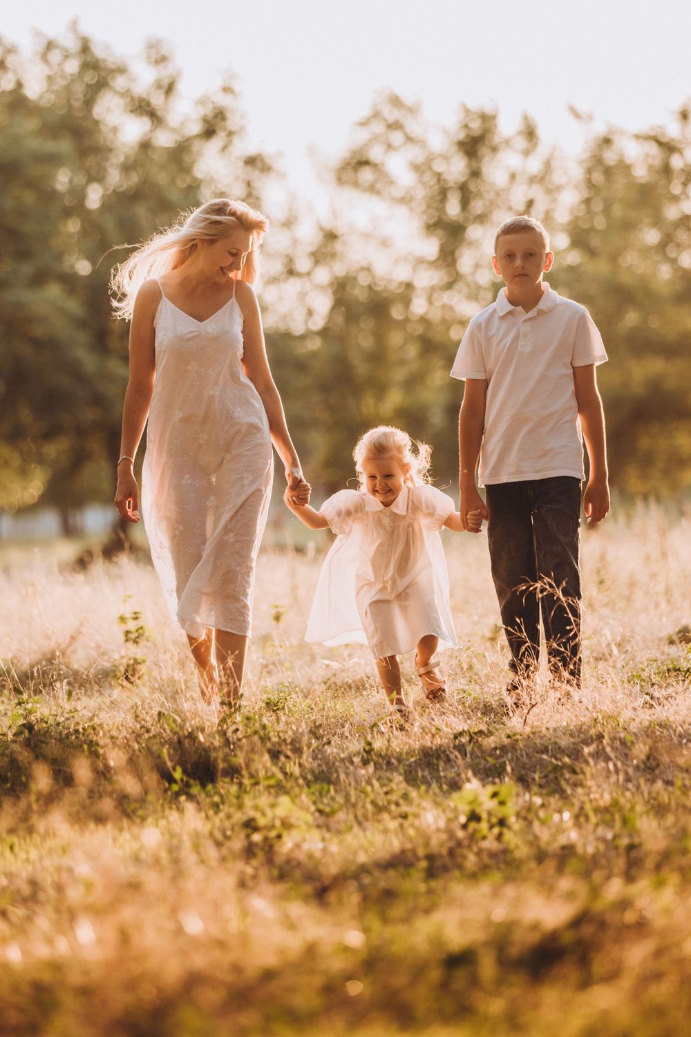 A family walks together through a sun-drenched meadow during golden hour.