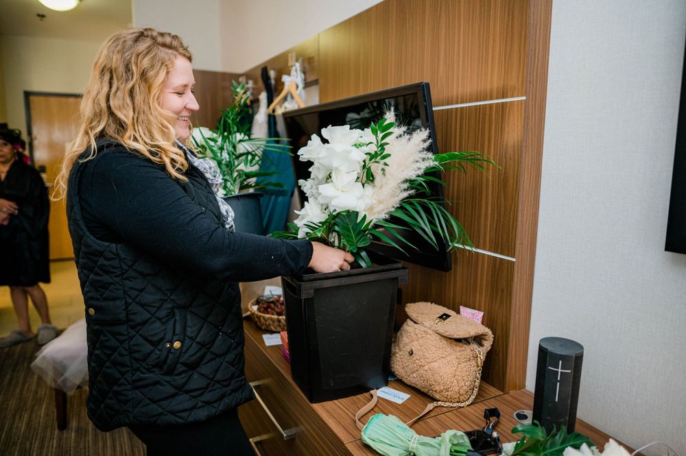 A person arranges floral decorations and greenery for a wedding setup.