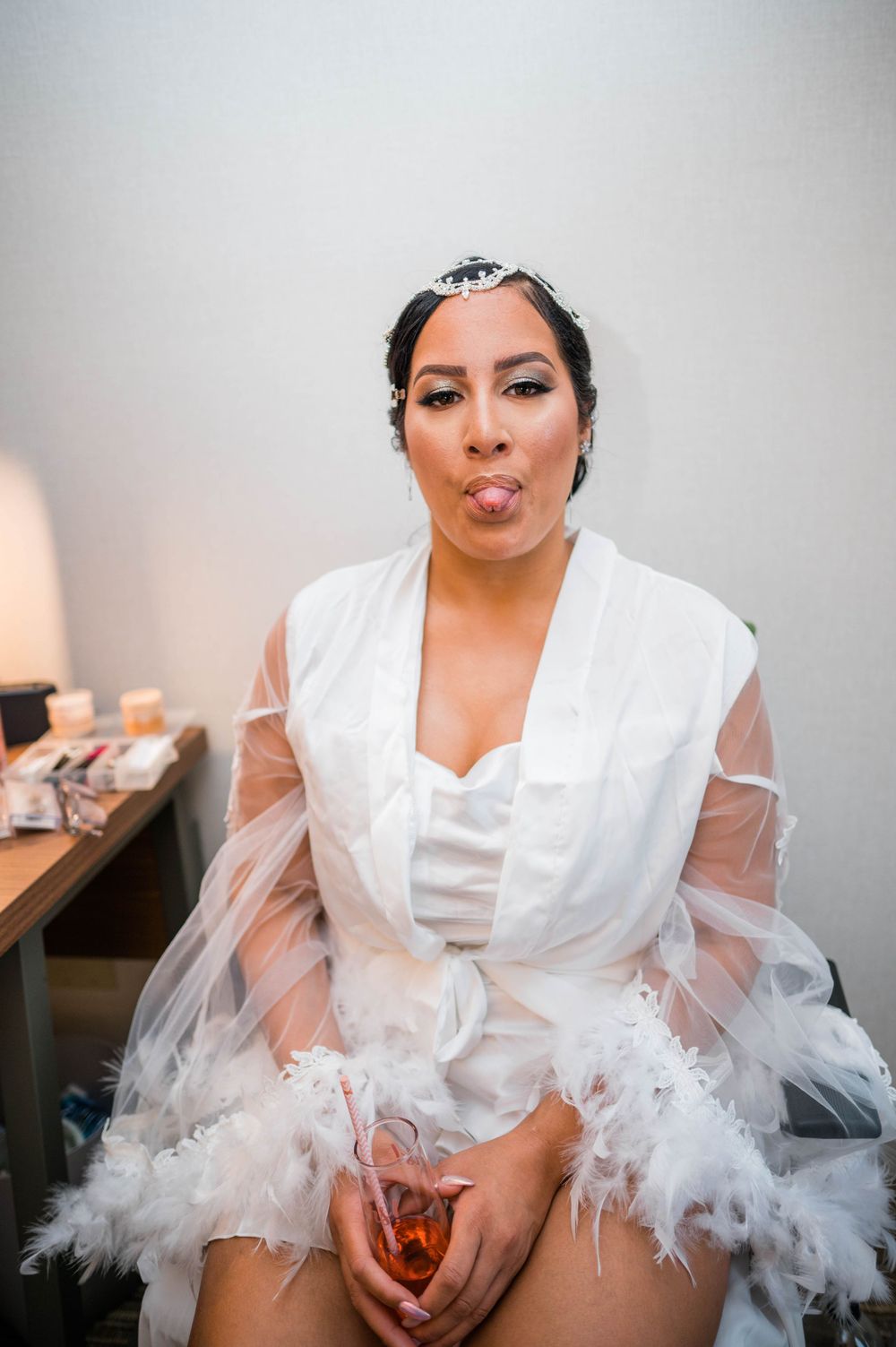 Bride in white robe making playful expression while getting ready.