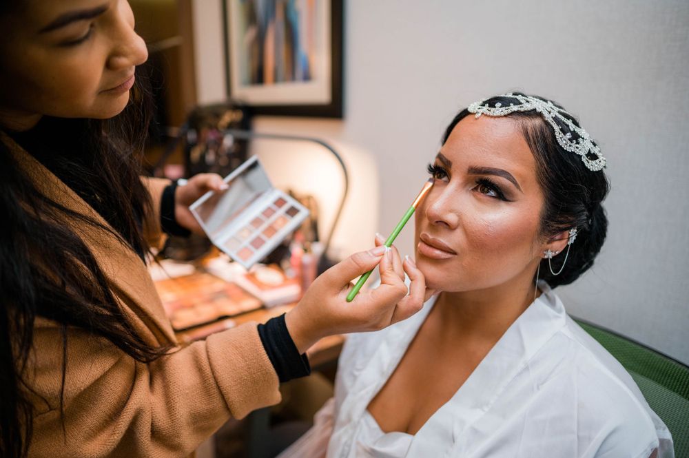 Makeup artist applies cosmetics with brush during wedding preparation.