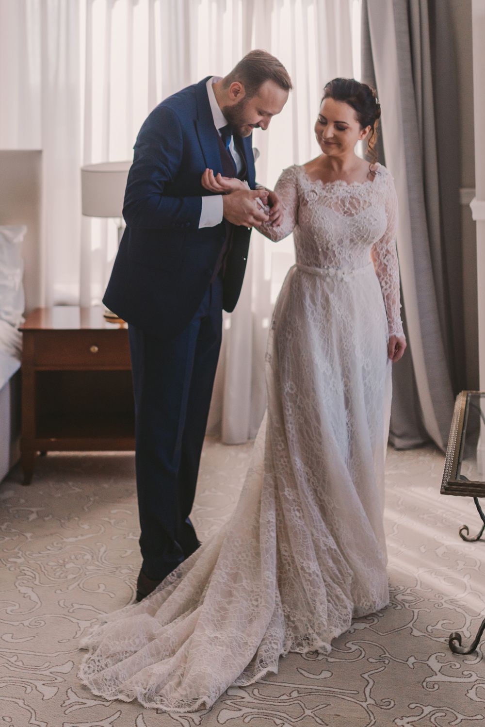 Close-up of dress details being adjusted in a sunlit room with white curtains.