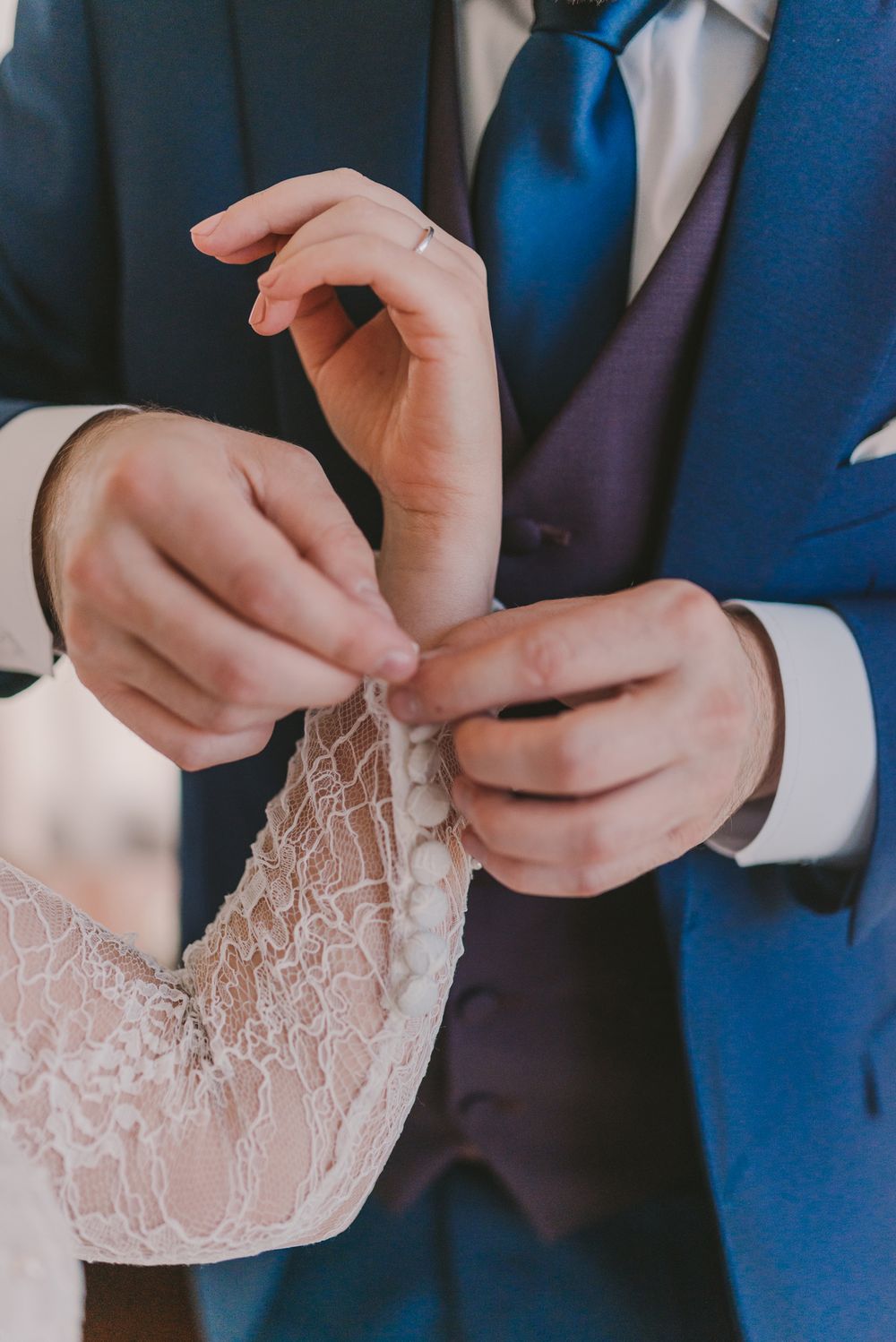 Detailed close-up of hands working with delicate lace fabric on formal attire.