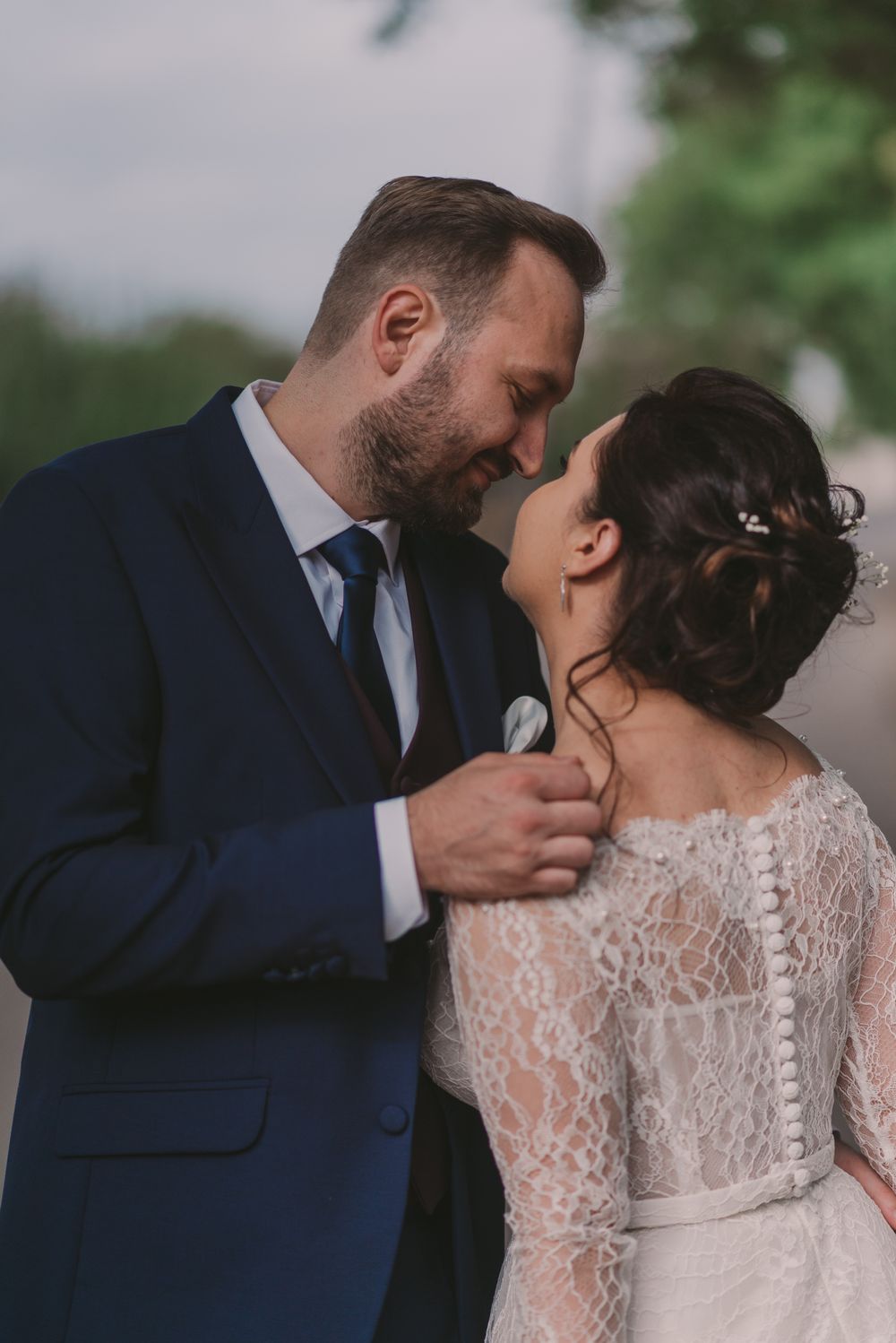 Intimate wedding moment captured between couple in navy suit and lace wedding dress.