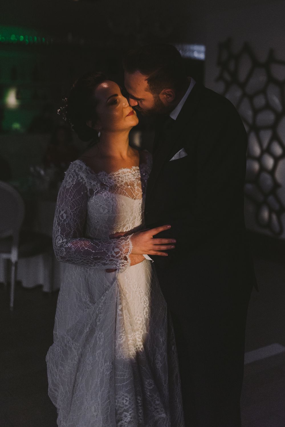 Romantic low-light dance between newlyweds at evening wedding reception.