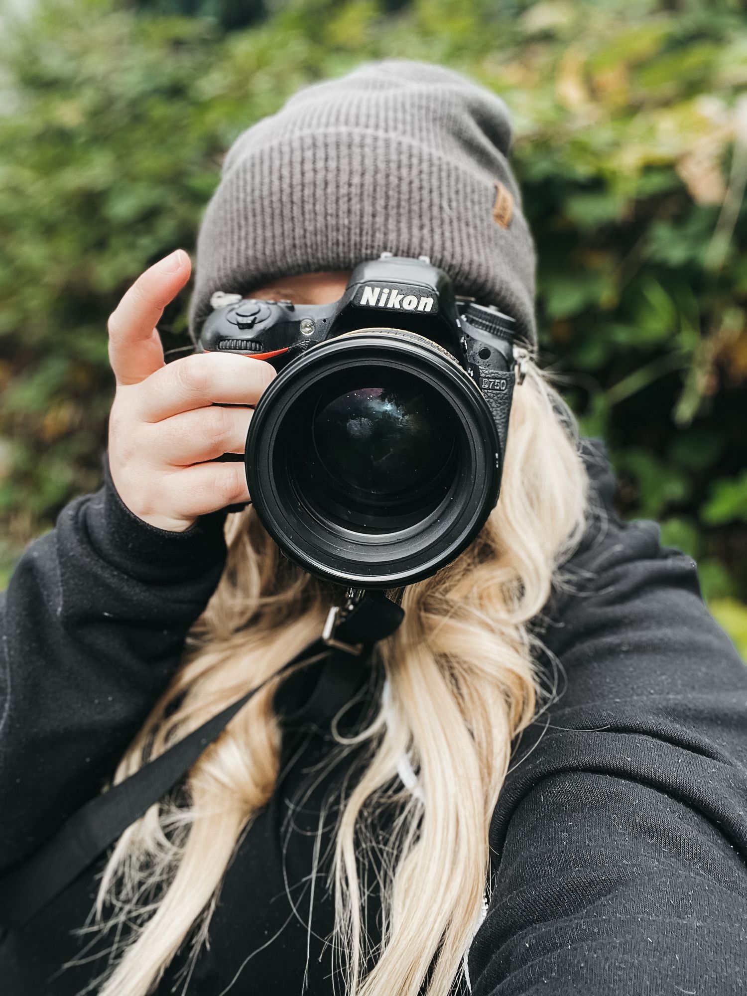 Close-up shots of photographer using Nikon camera while wearing gray beanie hat.