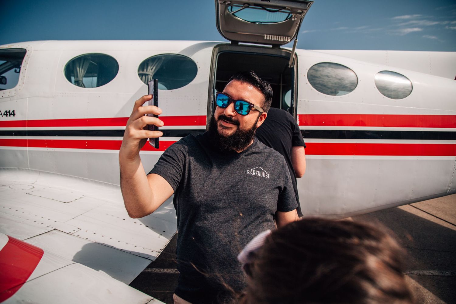 man standing in front of plane talking on facetime
