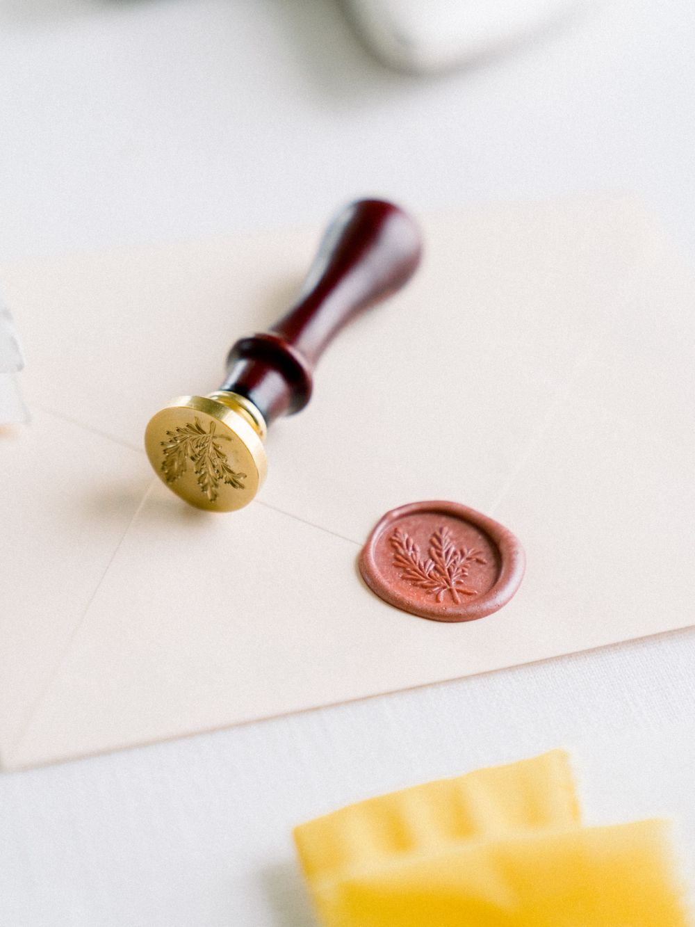 Vintage wax seal stamp and terracotta seal impression on cream paper with yellow ribbon.