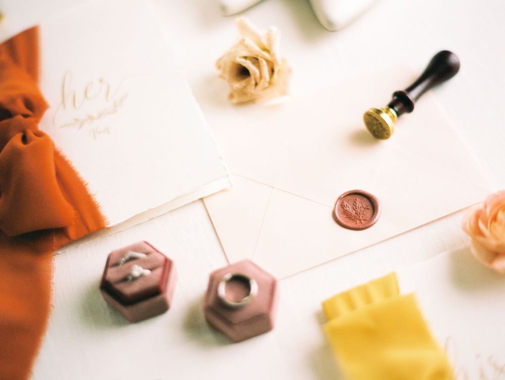 Wedding details including wax seals, roses, and styling accessories arranged on a white surface.