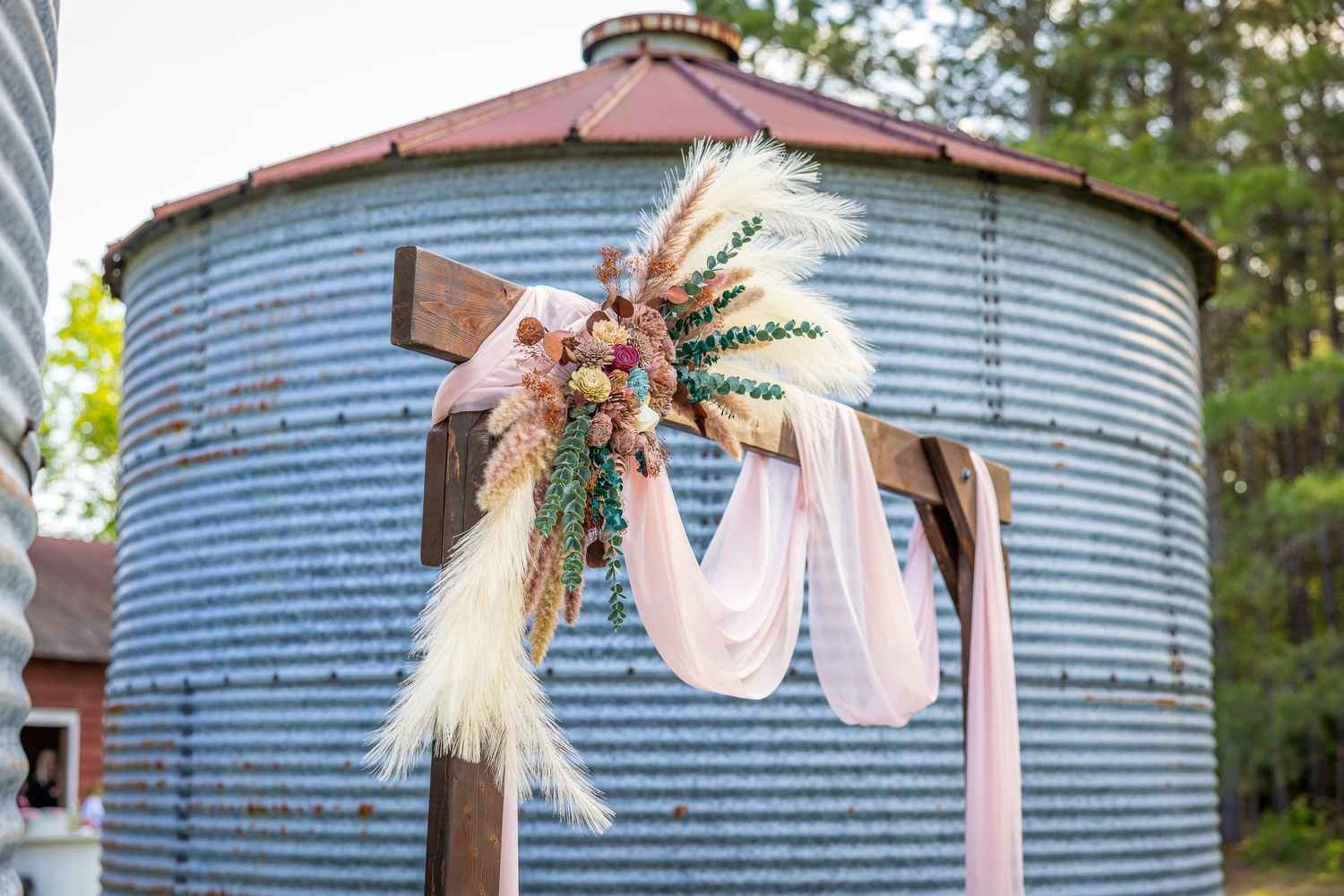Rustic wedding decor with dried flowers and fabric hanging on a metal silo structure.
